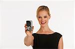 business woman holding up phone towards camera with copy space on white seamless background