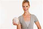 young woman holding up piggy bank on white seamless background