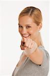 young woman pointing at camera with selective focus on white seamless background