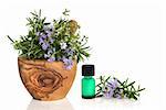 Rosemary and thyme herbs in flower in an olive wood mortar with pestle with an aromatherapy oil glass bottle and leaf sprig isolated over white background.