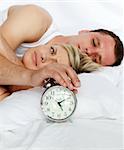 Young couple in bed with alarm clock going off