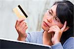 A young woman is thinking about using her credit card.