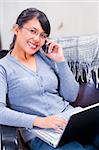 Portrait of a young Asian woman talking on the phone and facing camera.