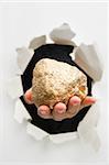 Hand breakthrough wall holding lump of golden nugget means breaktrhough in finance or similar things - one of the breakthrough series