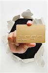 Hand holding gold credit card through cracked wall means breakthrough in credit card innovation - one of the breakthrough series