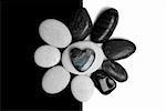 Two sets of pebbles on contrasting backgrounds with a stone heart in the centre