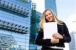 Blonde business woman posing in front of a modern blue office building