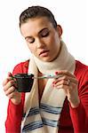 woman with a cup of hot drink looking sick checking her body temperature