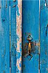 highly textured blue wooden gate with a bronze handle