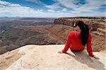 Woman overlooking Goosenecks State Park and Monument Valley, Utah, from Muley Point