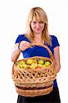 Woman in blue blouse standing and holding a basket full apples on white background.  Beautiful girl holding a basket of delicious fresh fruits. Pretty girl with basket of apples. Isolated over white.