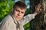 Close-up portrait of young man holding from a tree