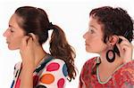 Two woman putting hearing aid into ear