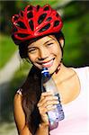 Excercise woman. Beautiful young woman enjoying a bottle of water outdoors during a bike trip