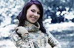 cute young brunette in a forest in winter looking in camera smiling