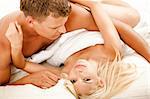 Mid adult couple in bed as woman looks at camera