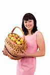 Girl in pink dress is standing and holding a basket full apples on white background. Pretty woman with basket of apples. Isolated over white. Beautiful girl holding a basket of delicious fresh fruits.