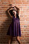 cute and sensual asian girl wearing purple nightgown posing against a brick wall