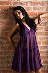 very cute asian fashion model wearing purple nightgown against a brick wall