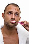 Man in a bathrobe brushing his teeth