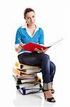 Beautiful female student sitting over a pile of folders, isolated on white