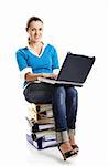 Beautiful female student sitting over a pile of folders working with a laptop