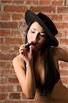 beautiful asian girl wearing a black bra and a black hat smoking a cigar
