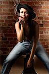 beautiful asian girl with jeans and hat sitting and smoking a cigar