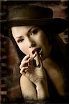 portrait of pretty young asian girl with black hat smoking a cigar