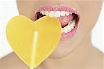 Heart shape candy on beautiful woman macro mouth