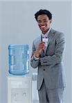 Afro-American businessman drinking from a water cooler in office