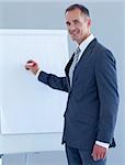 Mature businessman writing in a whiteboard in a presentation