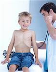 Attractive doctor examinating a little boy with stethoscope