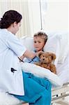 Female doctor listening to a child chest with stethoscope in bed