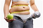 fat woman with unzup jeans holding apple and weight on each hand, id a concept to fight against obesity