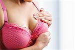 Woman doing self breast examination using pink bra
