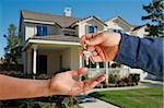 Handing Over the House Keys in Front of a Beautiful New Home.