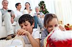 Children looking for presents in Christmas boots and family on sofa