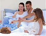 Brother and sister playing together in bed with their parents