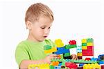 Little boy builds something of the plastic multi-coloured parts, isolated