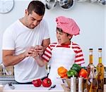 Boy cut his finger in kitchen cutting vegetables and father treating it