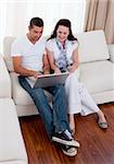 Happy couple using a laptop to buy online on sofa