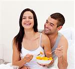 Happy young couple eating fruit in bed