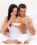 Happy woman and man having nutritive breakfast in bed