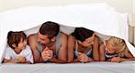 Family talking under the sheets in parent's bed