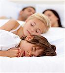 Young family sleeping together in parent's bed