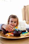 Hungry little girl looking at colorful confectionery at home
