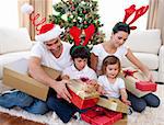 Happy young family opening Christmas presents at home