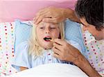 Father checking his daughter's temperature with a thermometer in bed