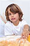 Little boy eating bread in the kitchen